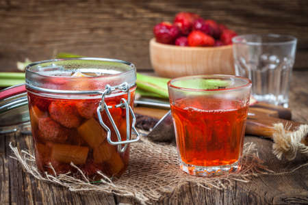 Homemade compote of rhubarb and strawberries on wooden table.の写真素材
