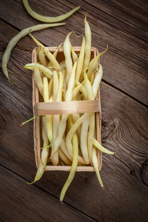 Yellow kidney beans in a basket on wooden table. Top view