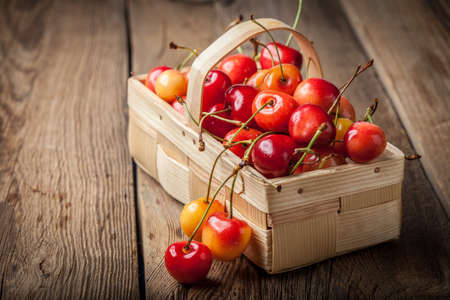Freshly picked cherries in a wooden basket. Dark light.の写真素材