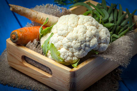 Fresh vegetables in wooden box on blue table.の写真素材