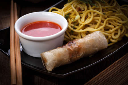 Tasty Chinese spring rolls with yellow noodles. Selective focus.