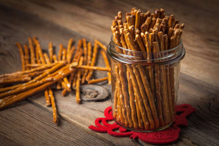 Salty pretzel sticks on a dark wooden table.の写真素材