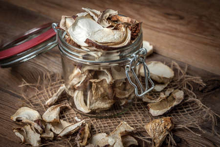Dried mushrooms in jar on a wooden background.の写真素材