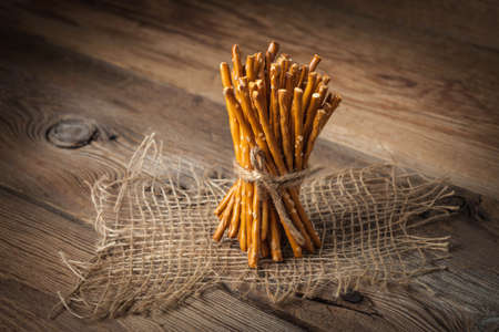 Salty pretzel sticks on a dark wooden table.