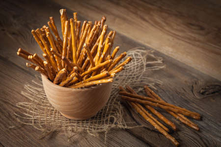 Salty pretzel sticks on a dark wooden table.