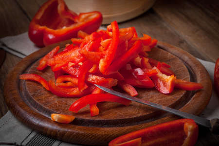 Red pepper cut into strips on wooden board.