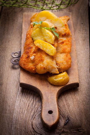 Fried fillet of cod with french fries on a wooden board. The selected focus point.の写真素材