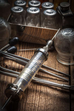 Retro syringe, stethoscope and medical cupping glass on a wooden table. Shallow depth of field.の写真素材