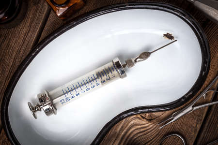 Retro syringe and medical cupping glass on a wooden table. Shallow depth of field.の写真素材