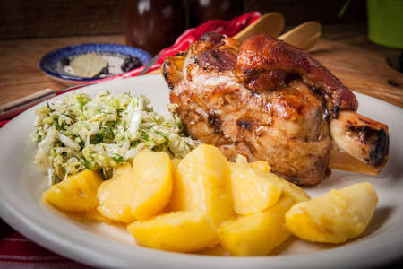 Pork knuckle with potatoes and cabbage on a white plate. Selective focus.の写真素材