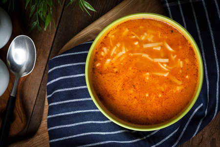 Tomato soup with noodles on a wooden table. Dark light. Top view.の写真素材