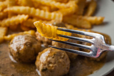 Meatballs with french fries in dill sauce and cranberry jam. Selective focus.