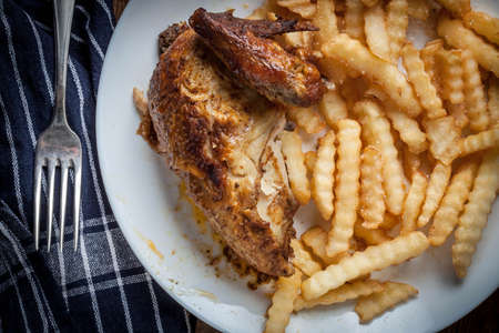 Roasted chicken with french fries on a plate. Selective focus. Top view.