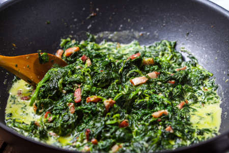 Spinach with bacon in a frying pan.の写真素材