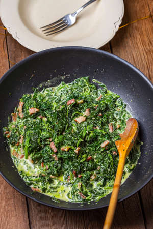 Spinach with bacon in a frying pan.の写真素材