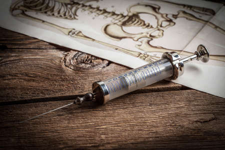 Retro syringe on a wooden table. Shallow depth of field.の写真素材