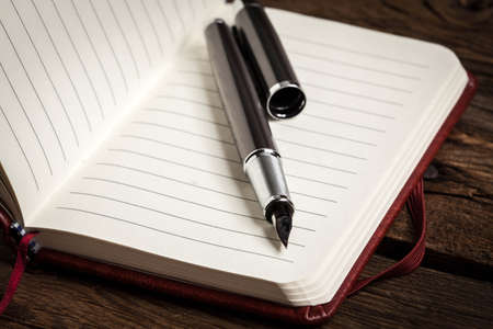 Opened blank notebook with elegant fountain pen on wooden background.の写真素材