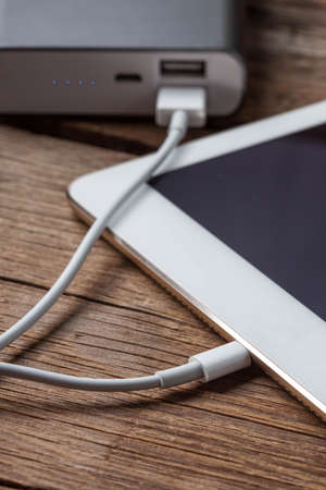 Smartphone charging with power bank on wood board.の写真素材