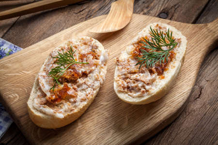 Hearty lard with greaves in a rustic stoneware pot served with fresh bread on a rustic wooden table....
