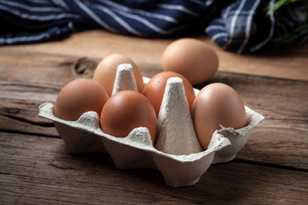 Fresh farm eggs on a wooden rustic background. Dark light.