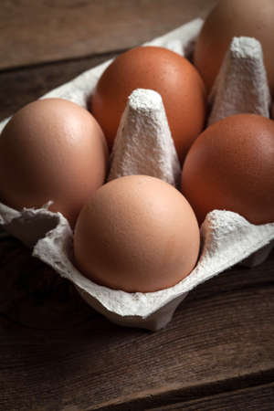 Fresh farm eggs on a wooden rustic background. Dark light.