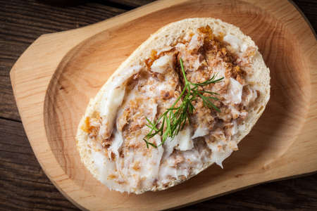 Hearty lard with greaves in a rustic stoneware pot served with fresh bread on a rustic wooden table. Dark light.の写真素材
