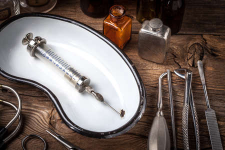 Retro syringe, stethoscope and medical cupping glass on a wooden table. Shallow depth of field.