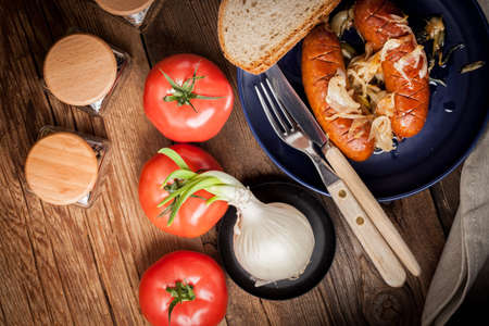 Fried sausage with onions in a plate.の写真素材