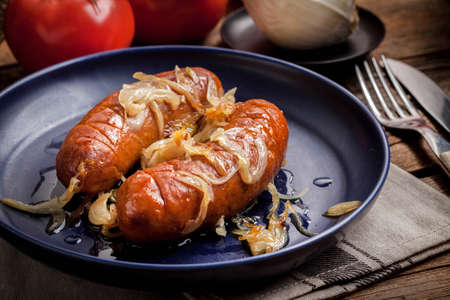 Fried sausage with onions in a plate.の写真素材