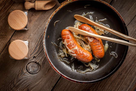 Fried sausage with onions in a frying pan.の写真素材