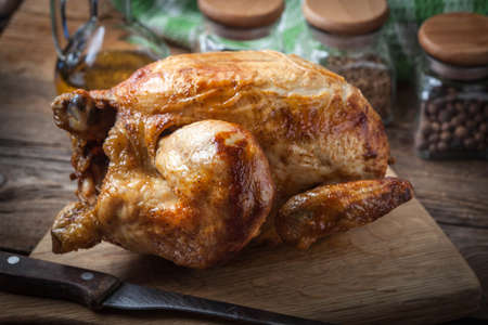 Whole roasted chicken on a chopping board.の写真素材
