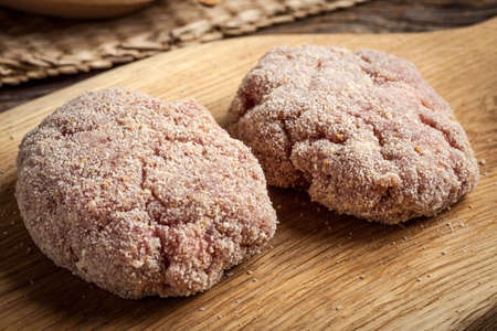 Raw meatballs rolled in a crispy bun on a chopping board prepared for baking.の写真素材