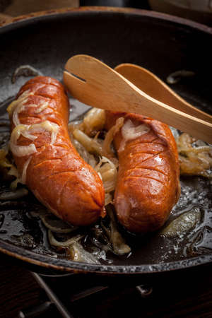 Fried sausage with onions in a frying pan.の写真素材