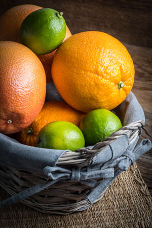 Fresh juicy citrus fruits in a basket on a wooden background.の写真素材