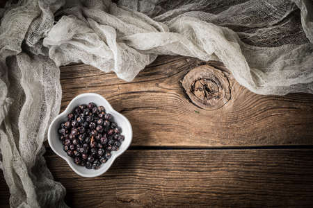 Grain of the herbs in the little bowl on a wooden board. Dark light. Copy space.