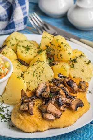 Fried chicken breast served with mushrooms and potatoes.の写真素材