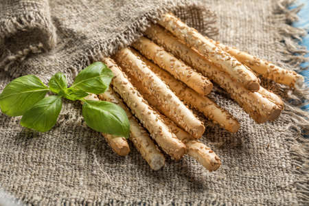 Fresh baked grissini bread on wooden board. Selective focus.