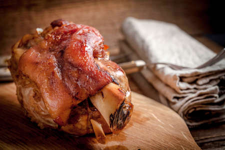 Roast pork knuckle on a wooden board. Selective focus.