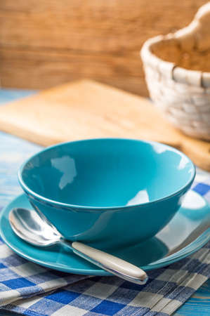 Bowls and plate with spoon and cloth on blue wooden background.の写真素材