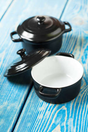 Mini black empty casserole on wooden table.
