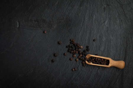 Seeds of pepper scattered on a stone black background. Top view, copy space.の写真素材
