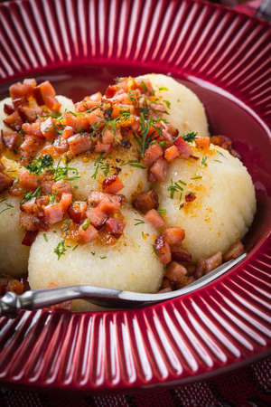 Potato dumplings with bacon, onion and ham on a plate.の写真素材