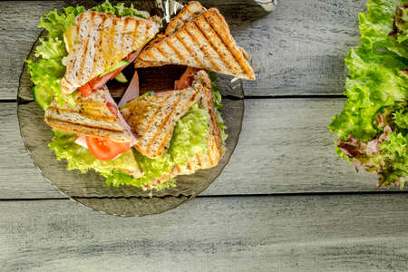 Panini sandwich with ham, tomato and lettuce  on a plate. Top view. Copy space.の写真素材