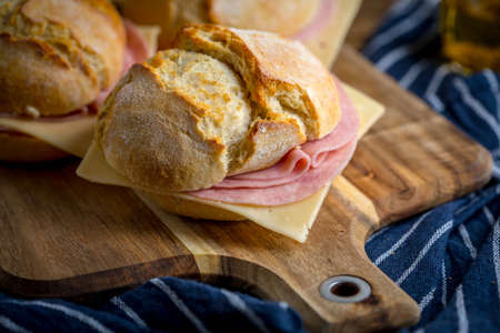 Sandwich with cheese and ground ham on a chopping board.