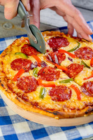 Cutting pepperoni pizza on sliced with special knife.の写真素材