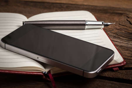 Opened blank notebook with elegant fountain pen on wooden background.の写真素材