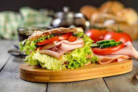 Sandwich with ham, cucumber, tomato and lettuce, with two layers of filling between three slices of toast.の写真素材