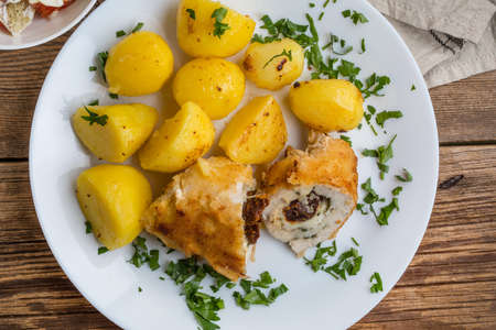 Baked chicken breast stuffed with cheese and dried tomatoes served with boiled potatoes. Top view.の写真素材
