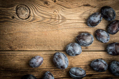 Garden plums on wooden table.  Top view with copy space for your text.の写真素材