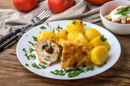 Baked chicken breast stuffed with cheese and dried tomatoes served with boiled potatoes.の写真素材
